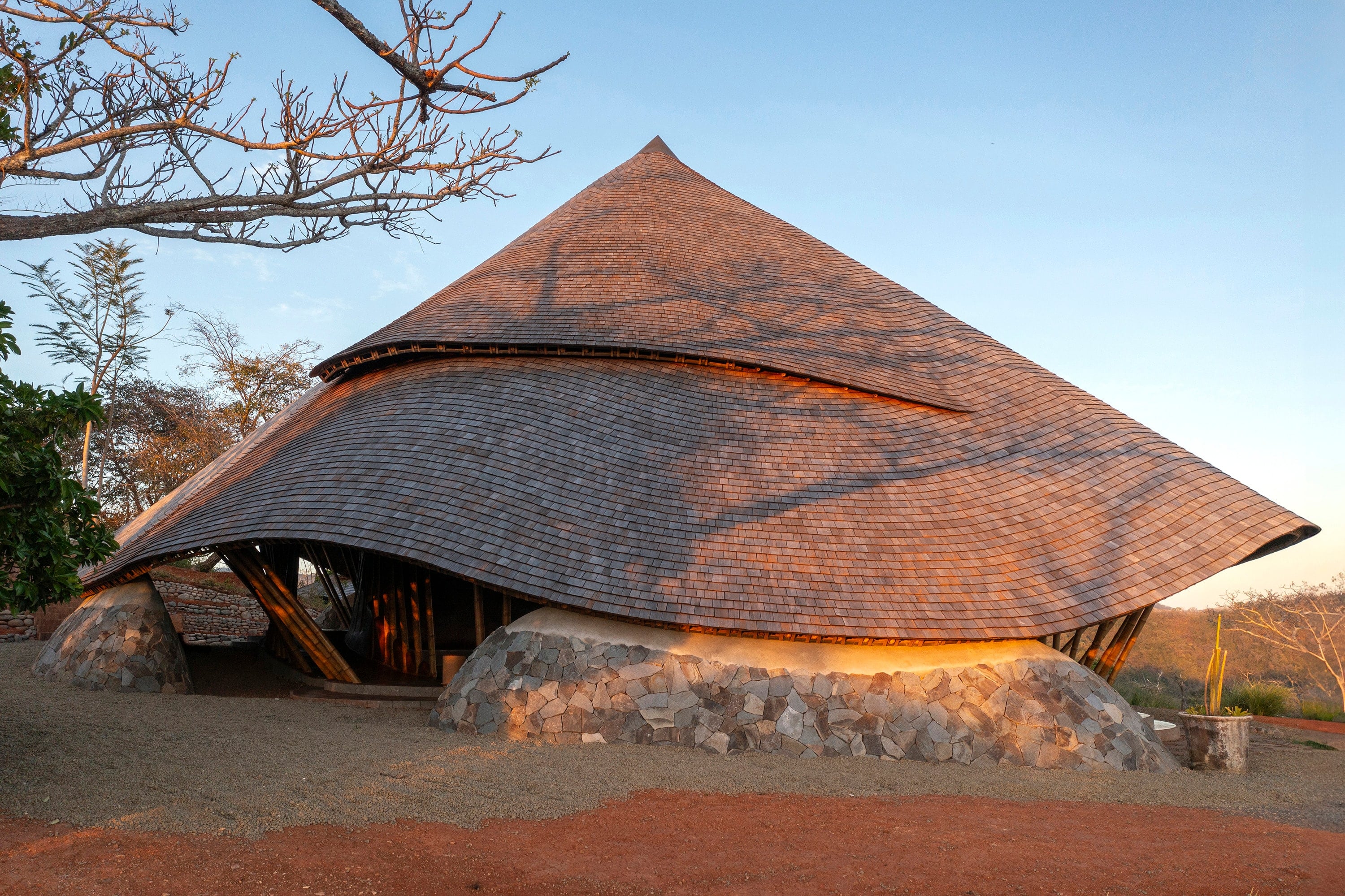 Conical shingle roof on a timber structure and a stone base