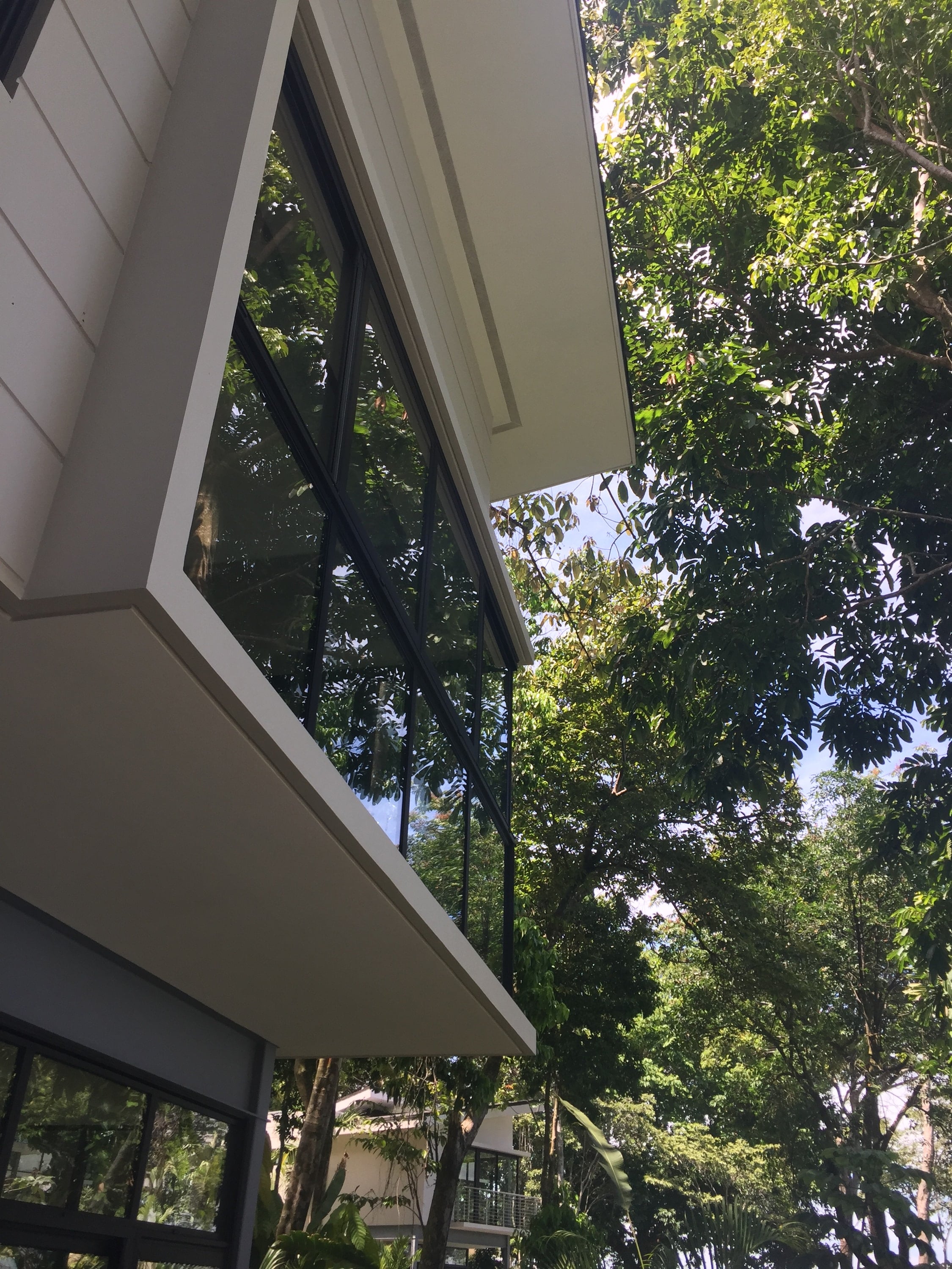 Corner of a white building with cantilevered windows, among trees.