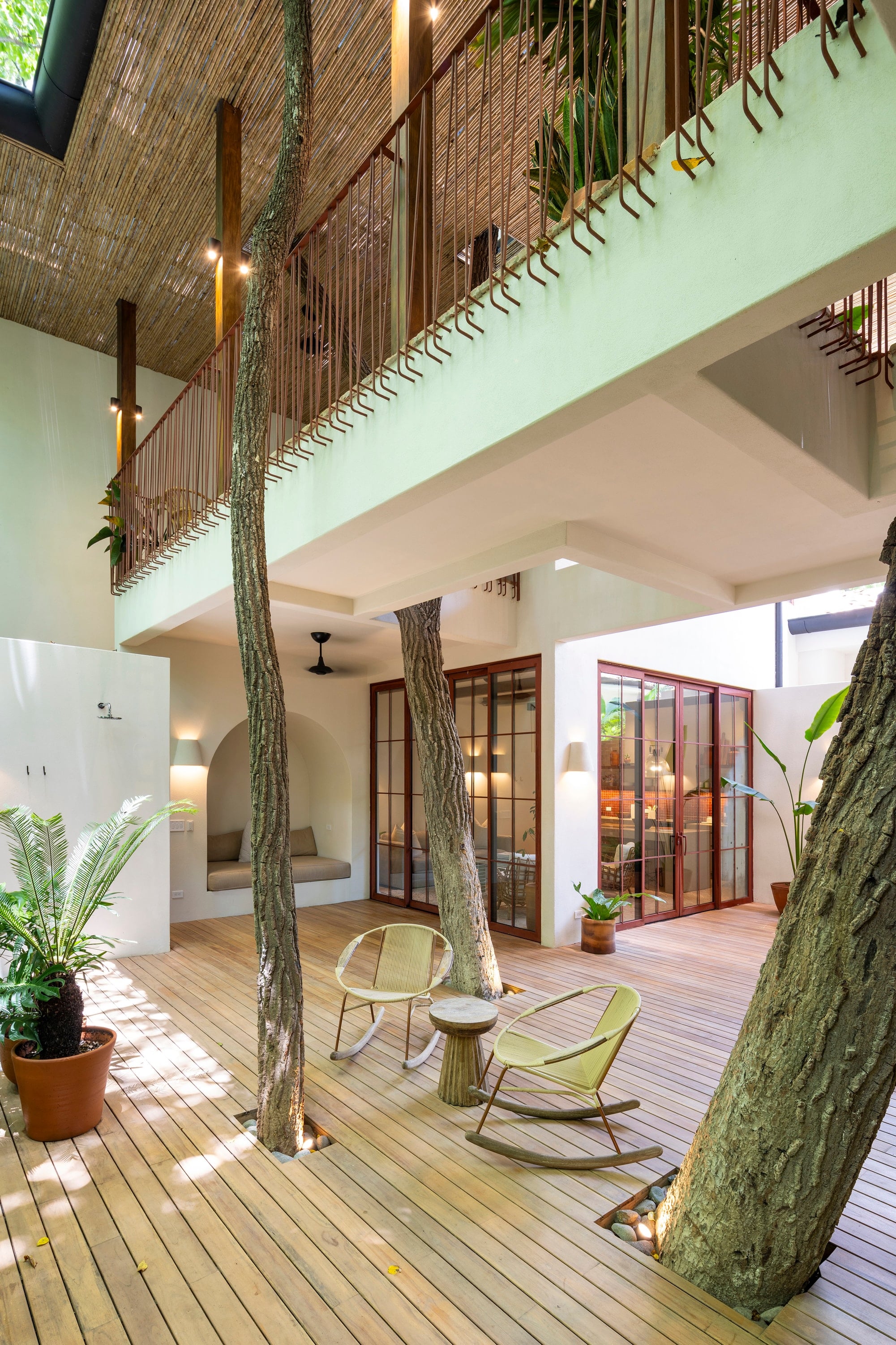 Patio interior de Villas Sendero con terraza de madera, árboles y balcones