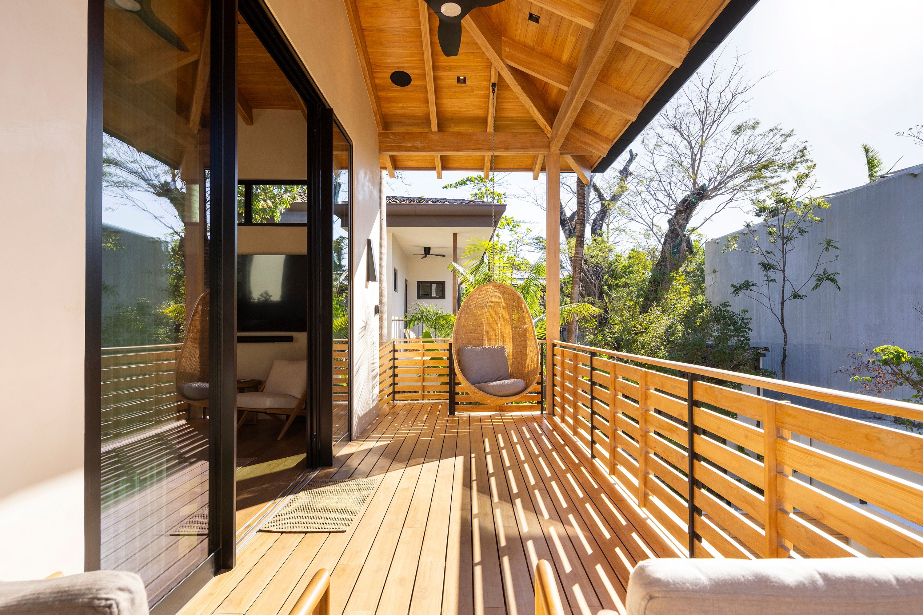 Terraza de madera con baranda y cubierta de madera abierta al jardín