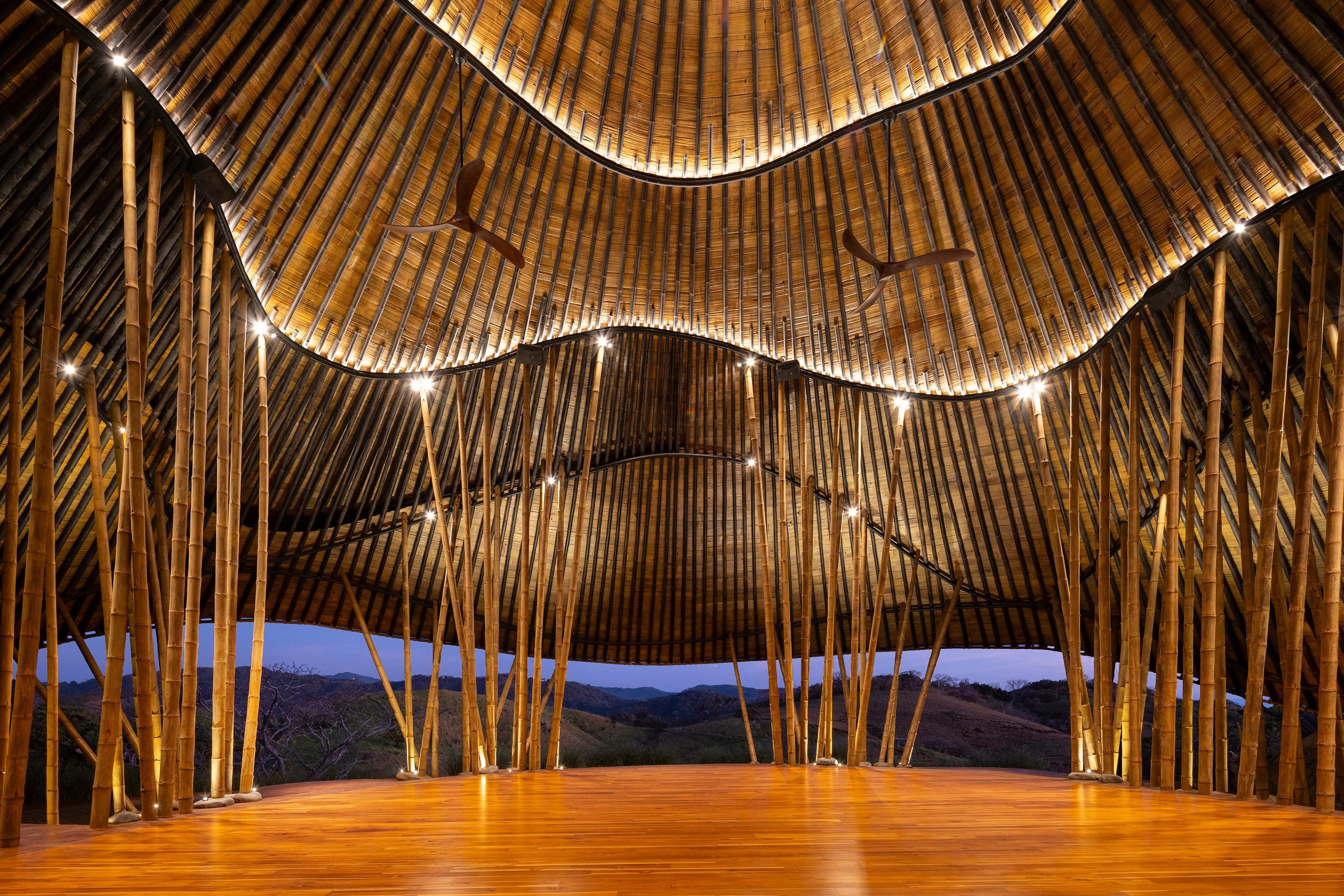 Interior with a bamboo structure and an undulating timber roof.