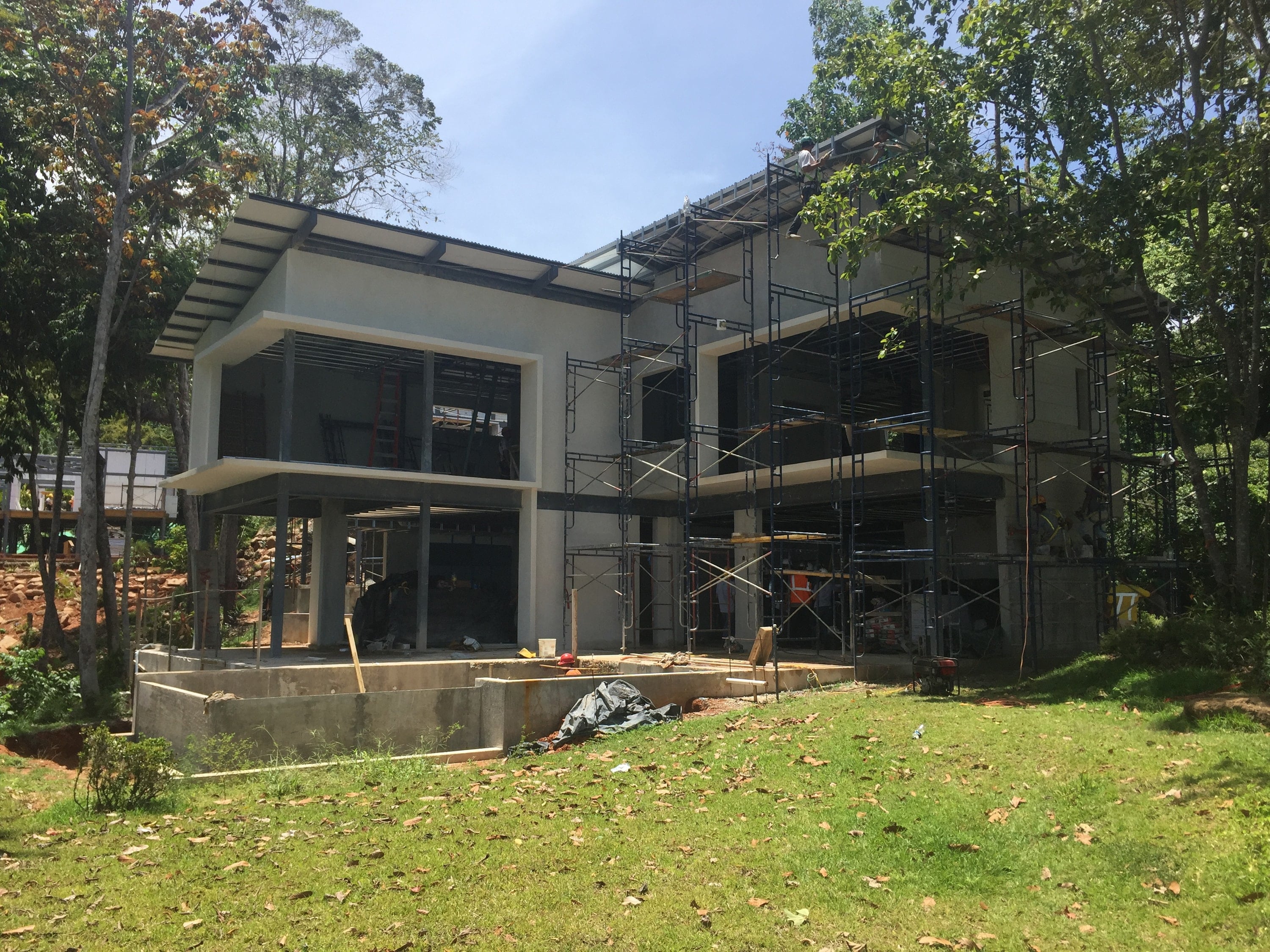 Two-storey building under construction, with scaffolding and large windows.