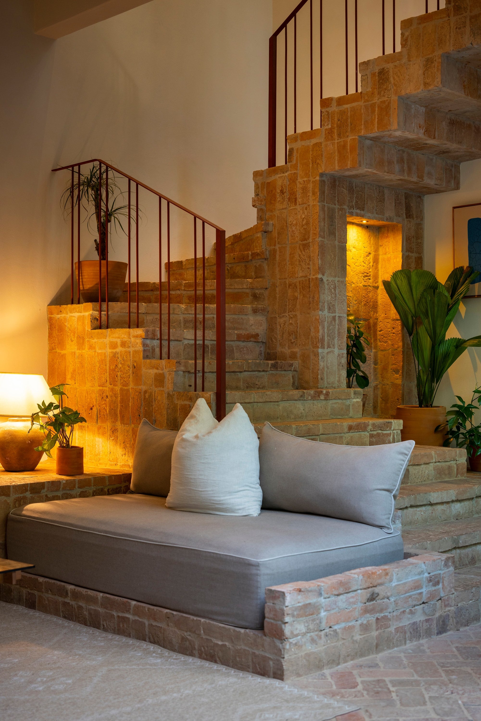 Villas Sendero: stone and brick staircase with a metal railing above a built-in sofa.